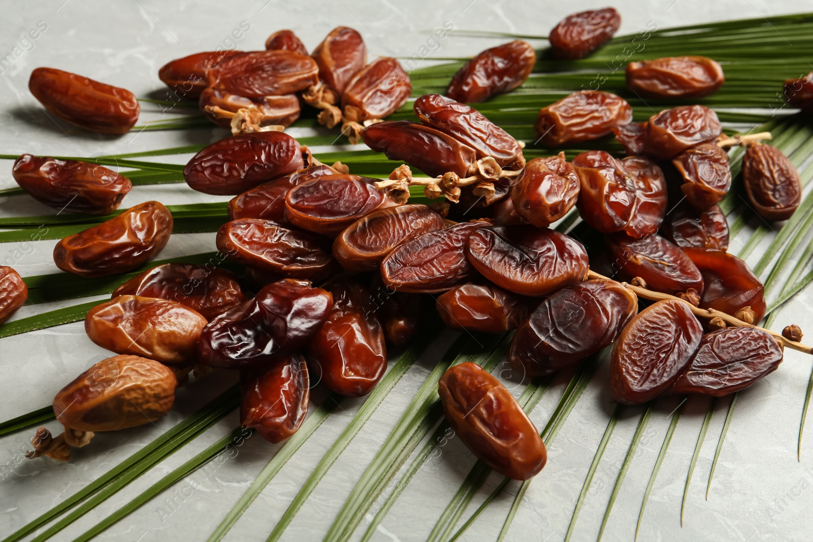 Photo of Tasty sweet dried dates and palm leaf on light table