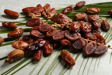 Tasty sweet dried dates and palm leaf on light table