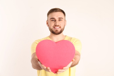 Young man with heart shaped box on white background