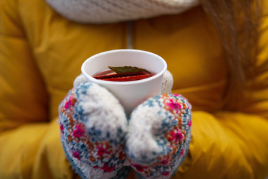Photo of Woman in yellow jacket holding cup of mulled wine, closeup