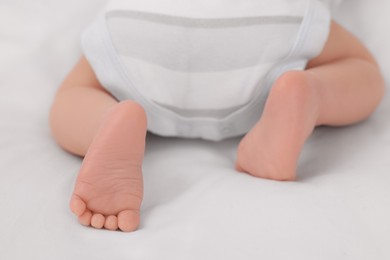 Newborn baby lying on white blanket, closeup