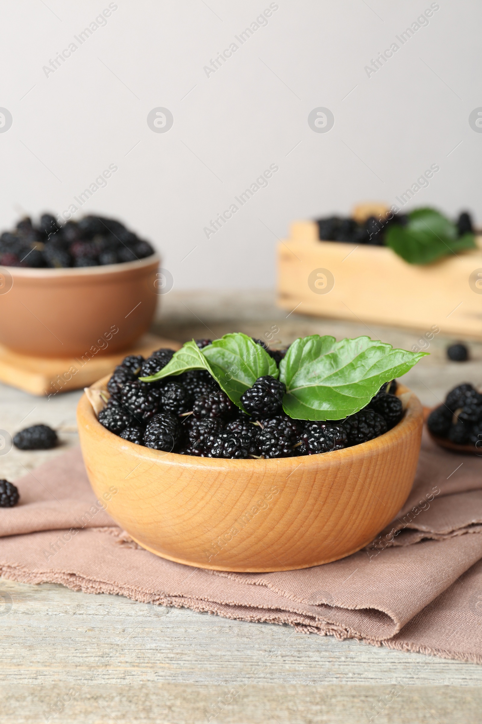 Photo of Bowl of delicious ripe black mulberries on wooden table