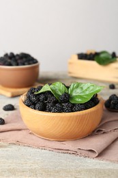 Photo of Bowl of delicious ripe black mulberries on wooden table