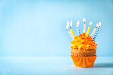 Photo of Delicious birthday cupcake with candles on color background