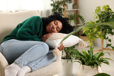 Photo of Relaxing atmosphere. Woman sleeping near beautiful houseplants at home