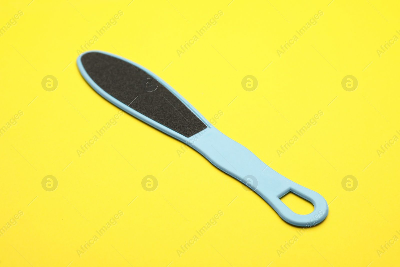 Photo of Light blue foot file on yellow background. Pedicure tool