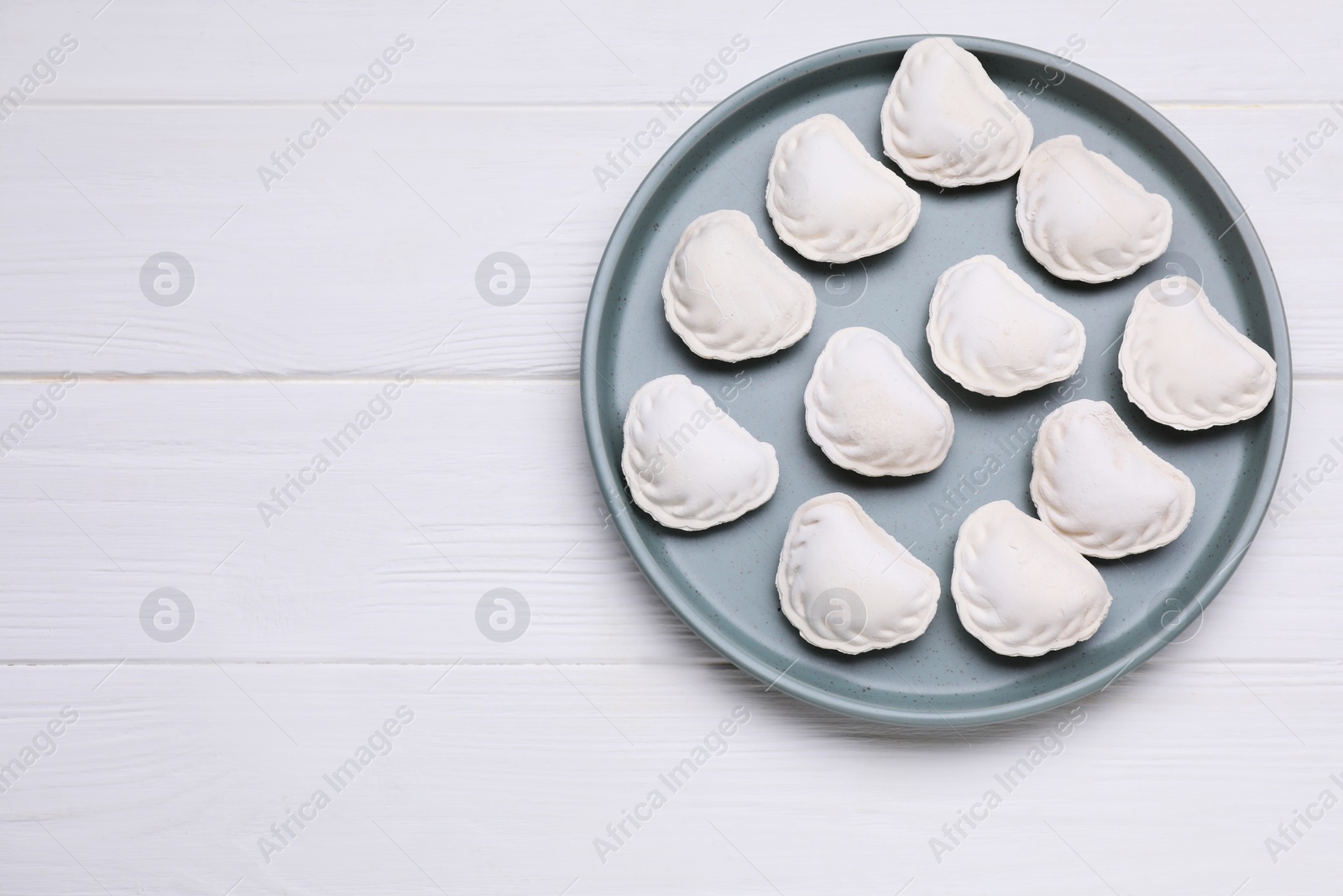 Photo of Raw dumplings (varenyky) on white wooden table, top view. Space for text