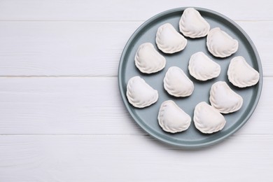 Raw dumplings (varenyky) on white wooden table, top view. Space for text