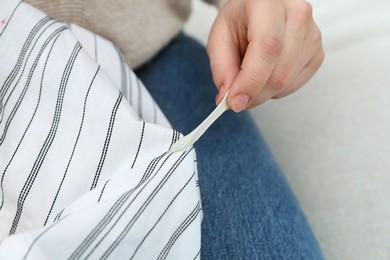 Photo of Woman removing chewing gum from shirt, closeup