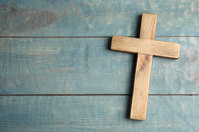 Photo of Christian cross on light blue wooden background, top view with space for text. Religion concept