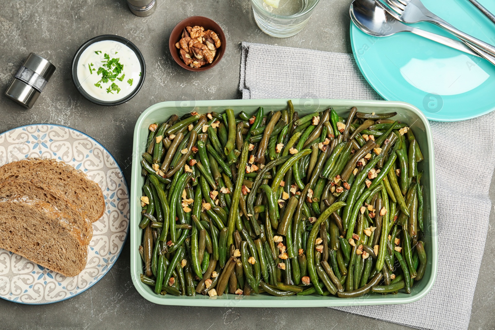 Photo of Dish with tasty green beans and nuts served for dinner on table, top view