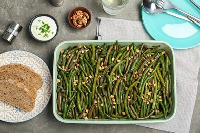 Photo of Dish with tasty green beans and nuts served for dinner on table, top view