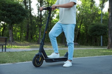 Photo of Man with modern electric kick scooter in park, closeup