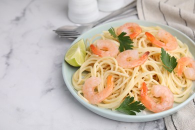 Photo of Tasty spaghetti with shrimps, lime and parsley on white marble table. Space for text