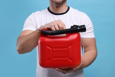 Man holding red canister on light blue background, closeup