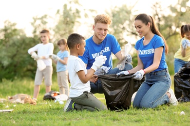 Photo of Little African-American boy collecting trash with volunteers in park