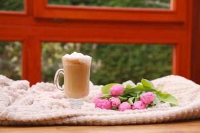 Photo of Glass of delicious cocoa and pink tulips on light blanket at terrace, space for text