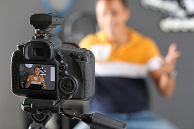Photo of Sport blogger recording video indoors, selective focus on camera display. Space for text