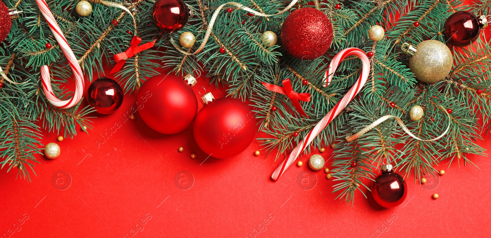 Photo of Fir tree branches with Christmas decoration on red background, flat lay. Space for text