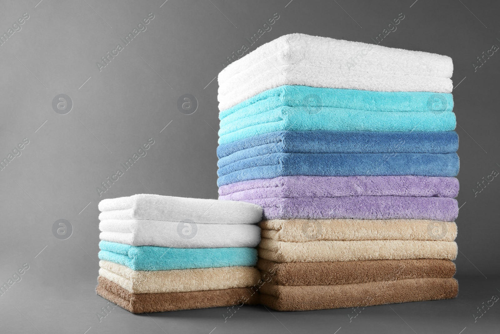 Photo of Different fresh soft terry towels on grey background