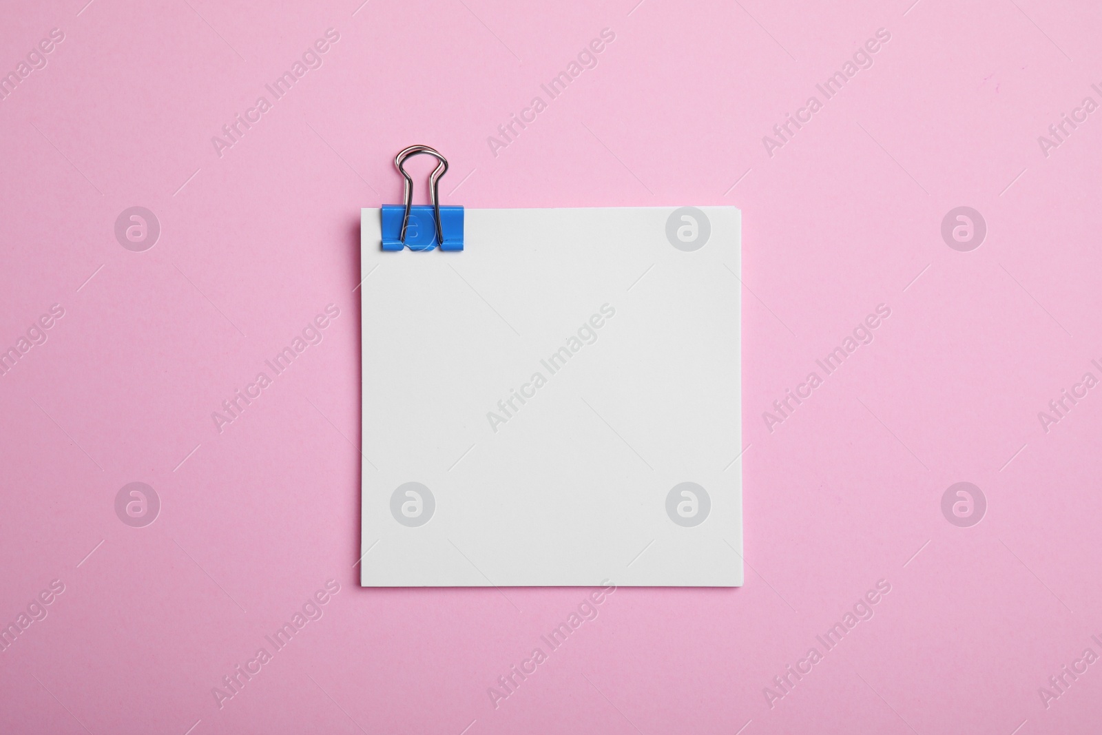 Photo of Sheet of paper with clip on pink background, top view