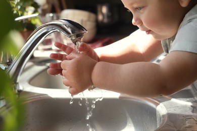 Little child washing hands in kitchen, closeup view