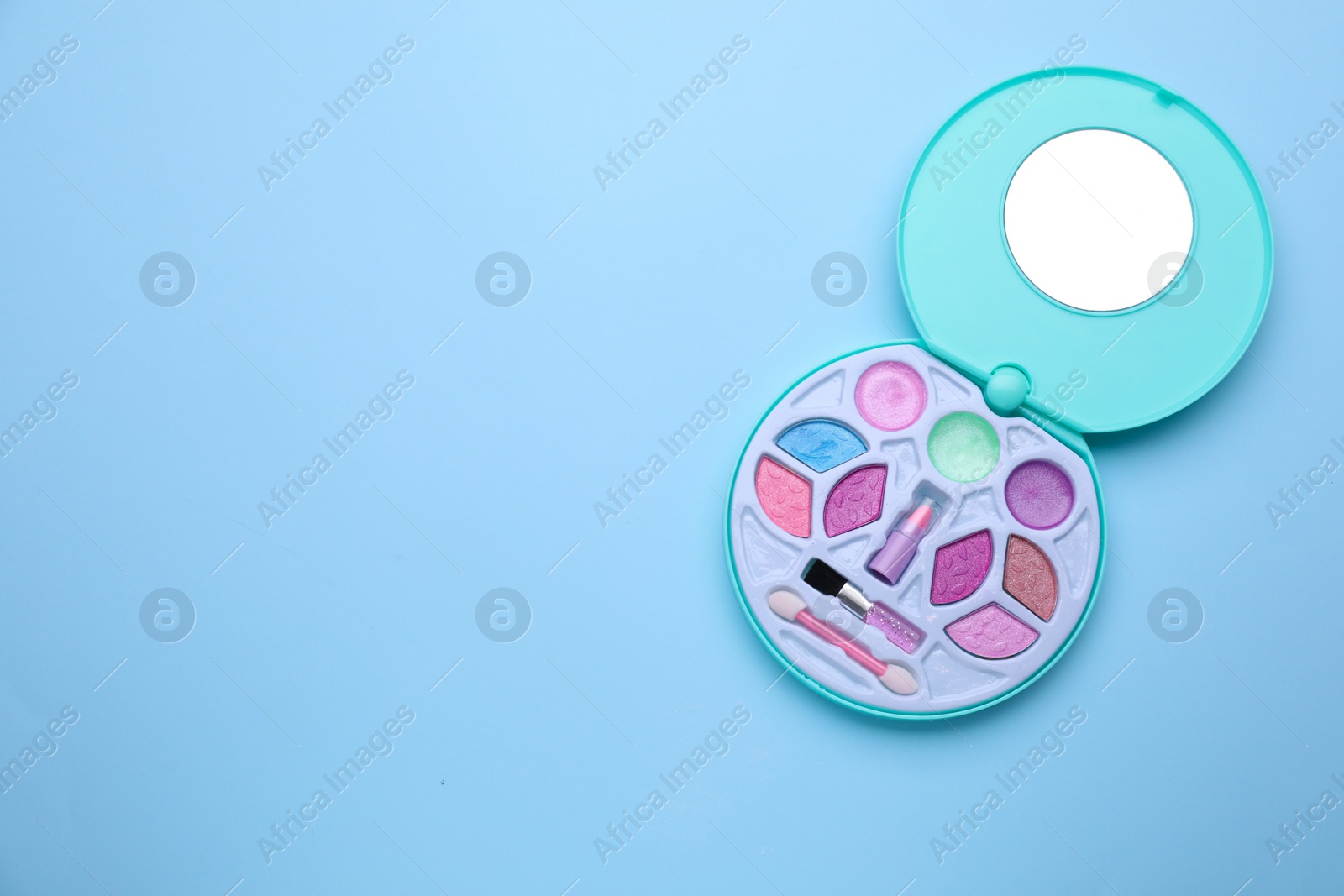 Photo of Decorative cosmetics for kids. Eye shadow palette with lipstick on light blue background, top view. Space for text
