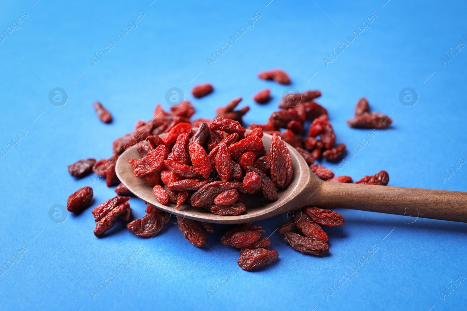 Photo of Dried goji berries on blue background, closeup