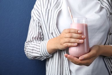 Image of Woman with glass of tasty smoothie on blue background, closeup