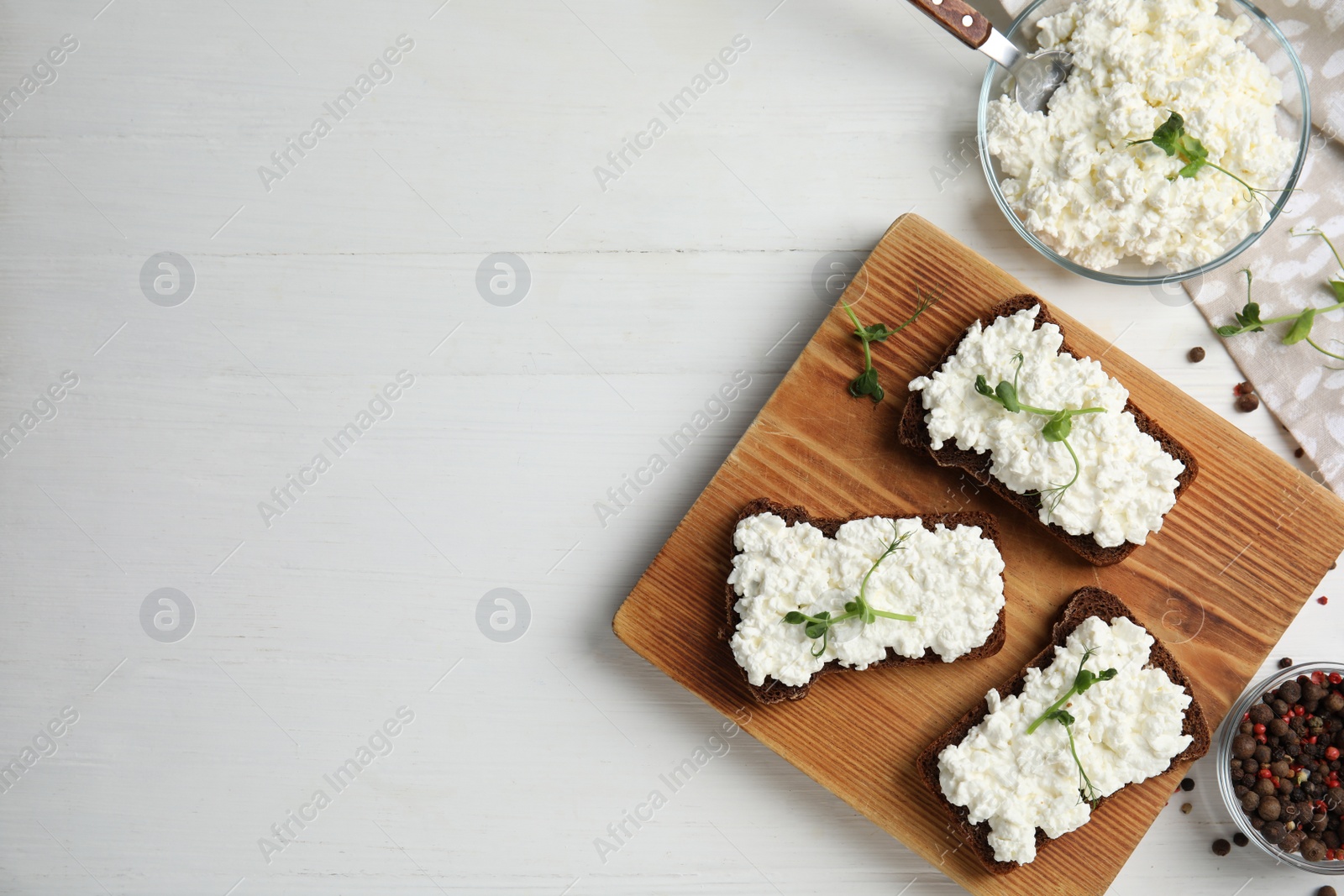 Photo of Bread with cottage cheese and microgreens on white wooden table, flat lay. Space for text