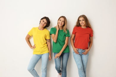 Group of young women in jeans and colorful t-shirts on light background