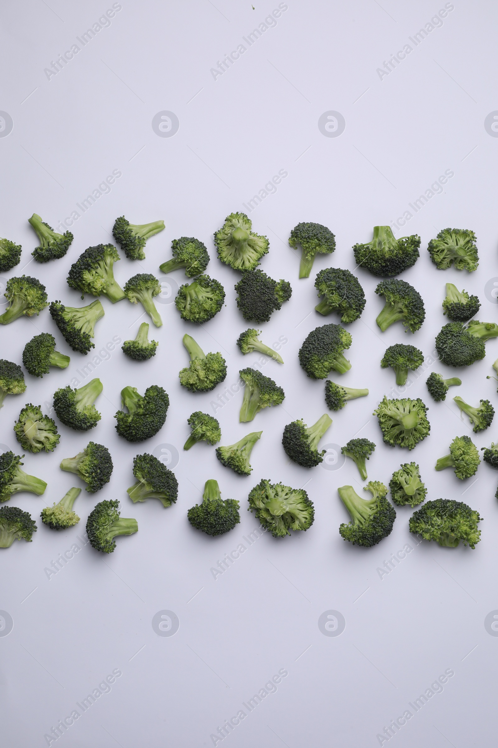 Photo of Many fresh green broccoli pieces on white background, flat lay