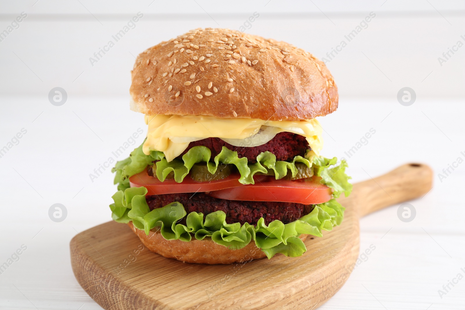 Photo of Delicious vegetarian burger on white wooden table