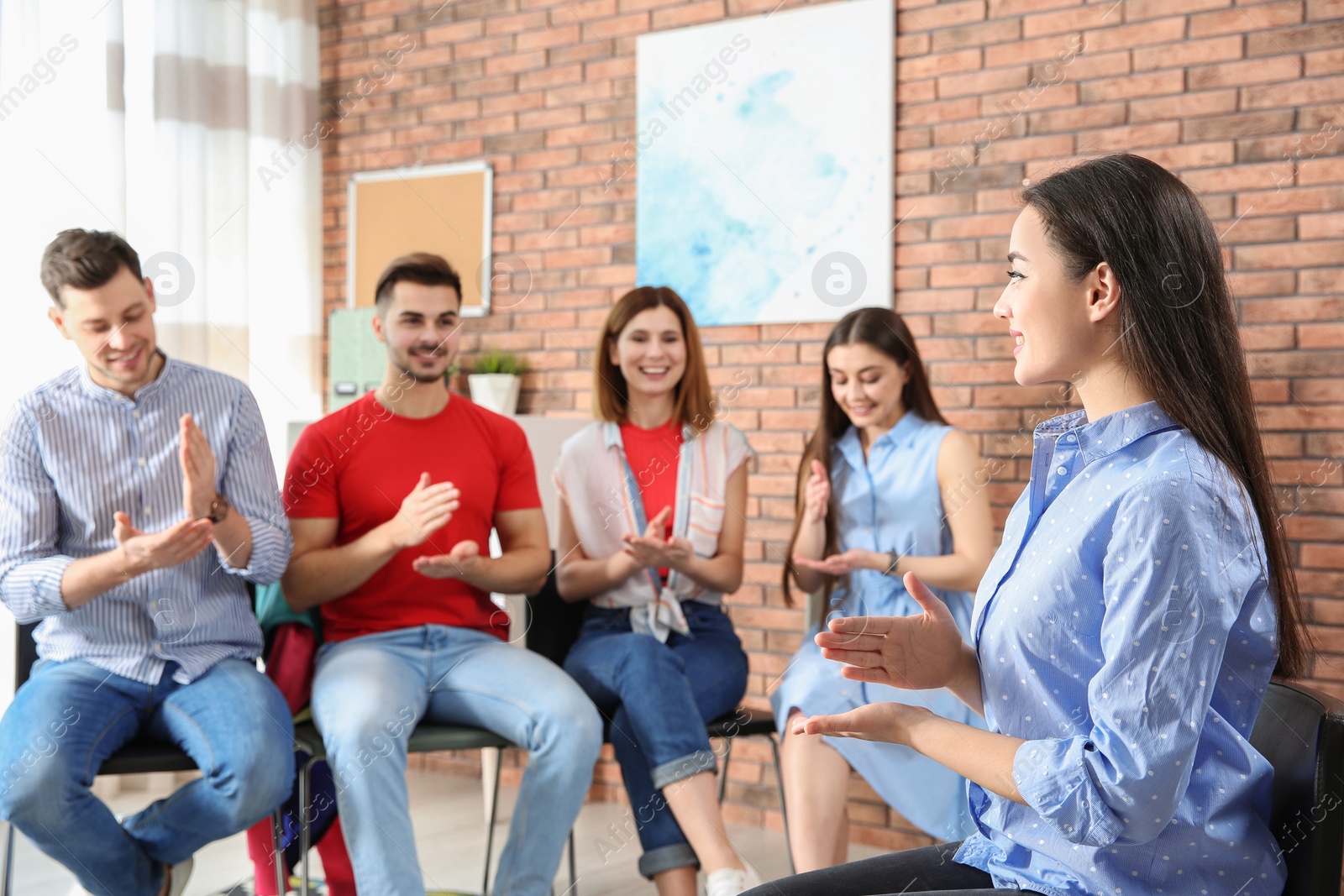 Photo of Group of young people learning sign language with teacher indoors