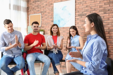 Photo of Group of young people learning sign language with teacher indoors