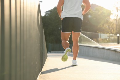 Man running outdoors on sunny day, closeup. Space for text