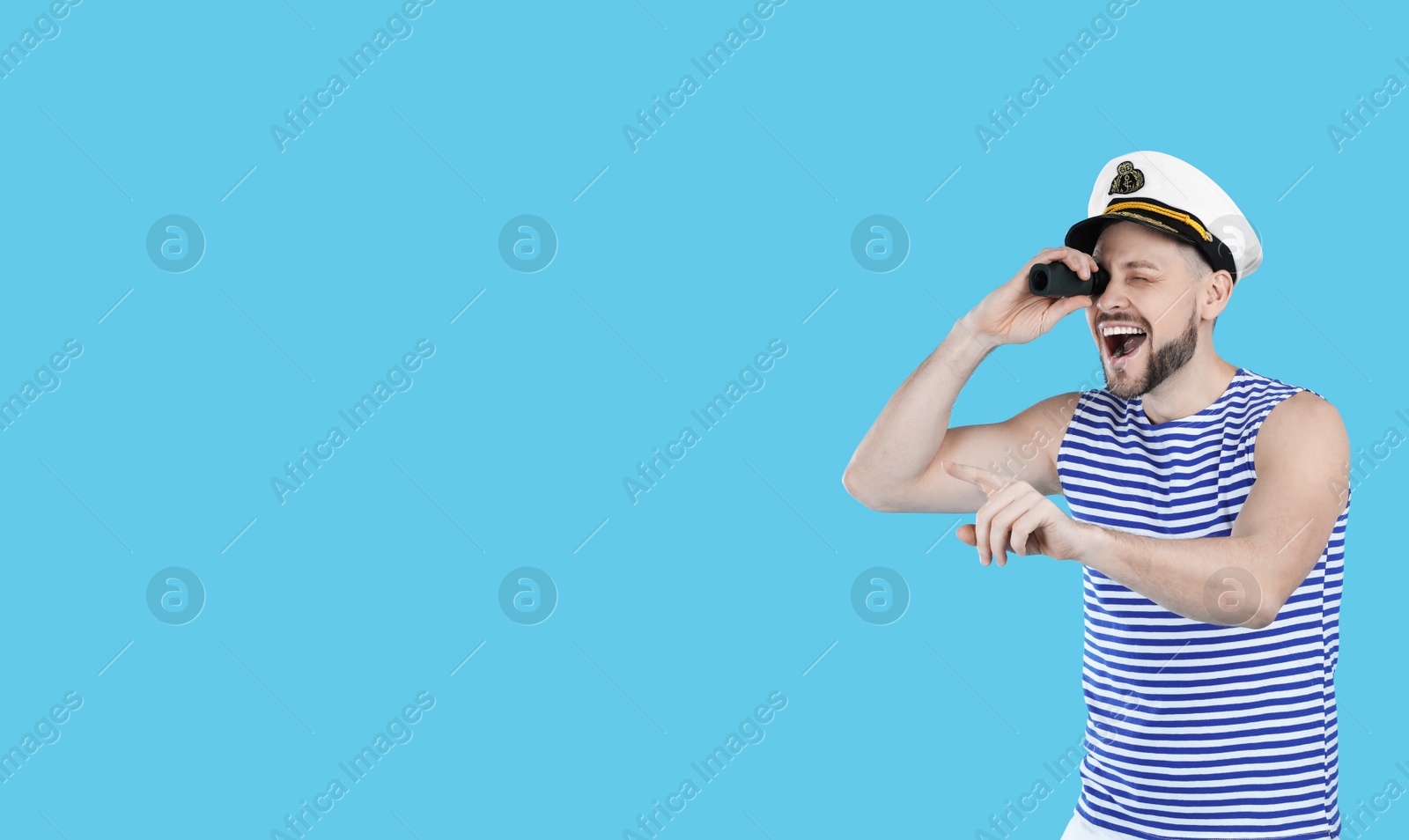 Photo of Sailor looking through monocular and pointing on light blue background