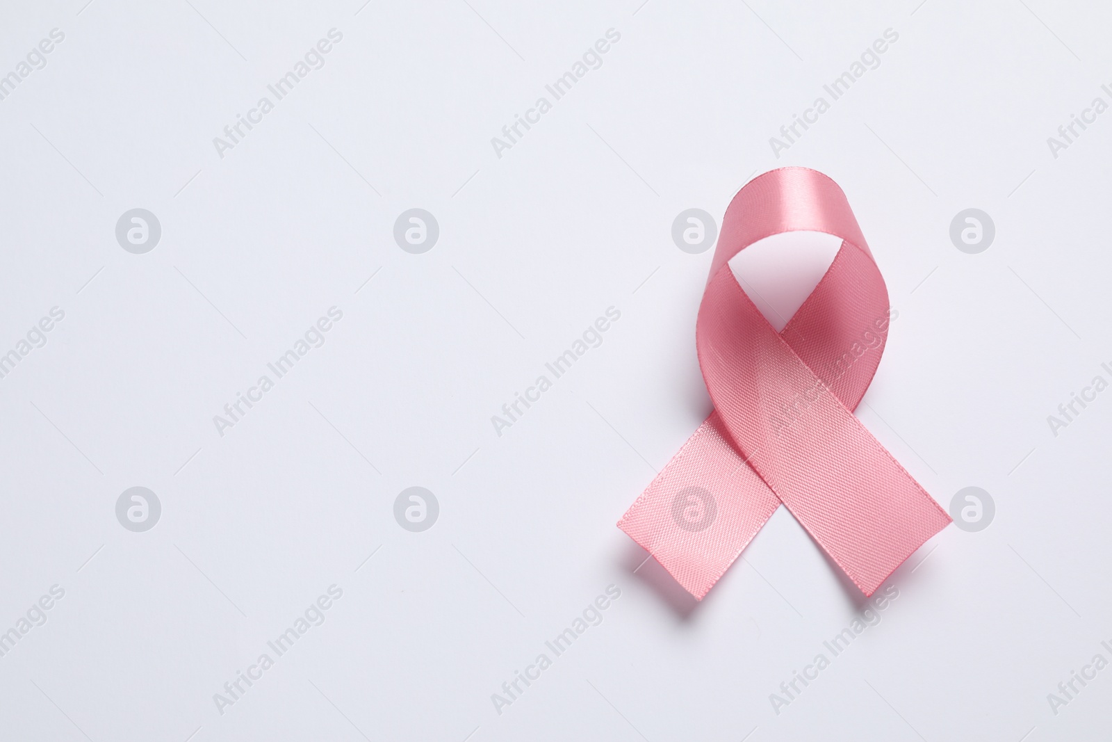 Photo of Pink ribbon on white background, top view and space for text. Breast cancer awareness