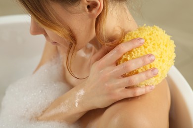 Woman with sponge taking bubble bath, closeup