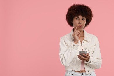 Beautiful young woman with smartphone on pink background. Space for text