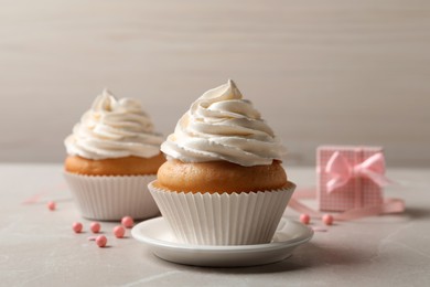 Photo of Delicious cupcakes decorated with cream on light grey table