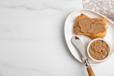 Photo of Crispy crackers with delicious meat pate and knife on white marble table, flat lay. Space for text