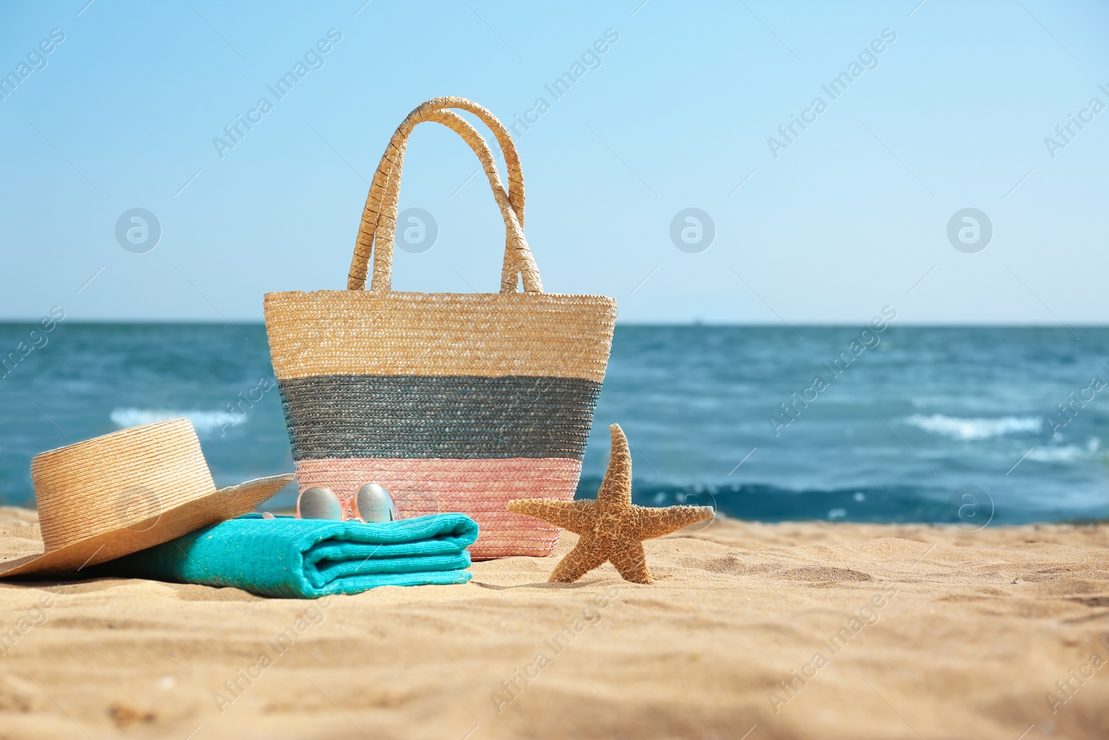 Photo of Stylish beach accessories on sand near sea. Space for text