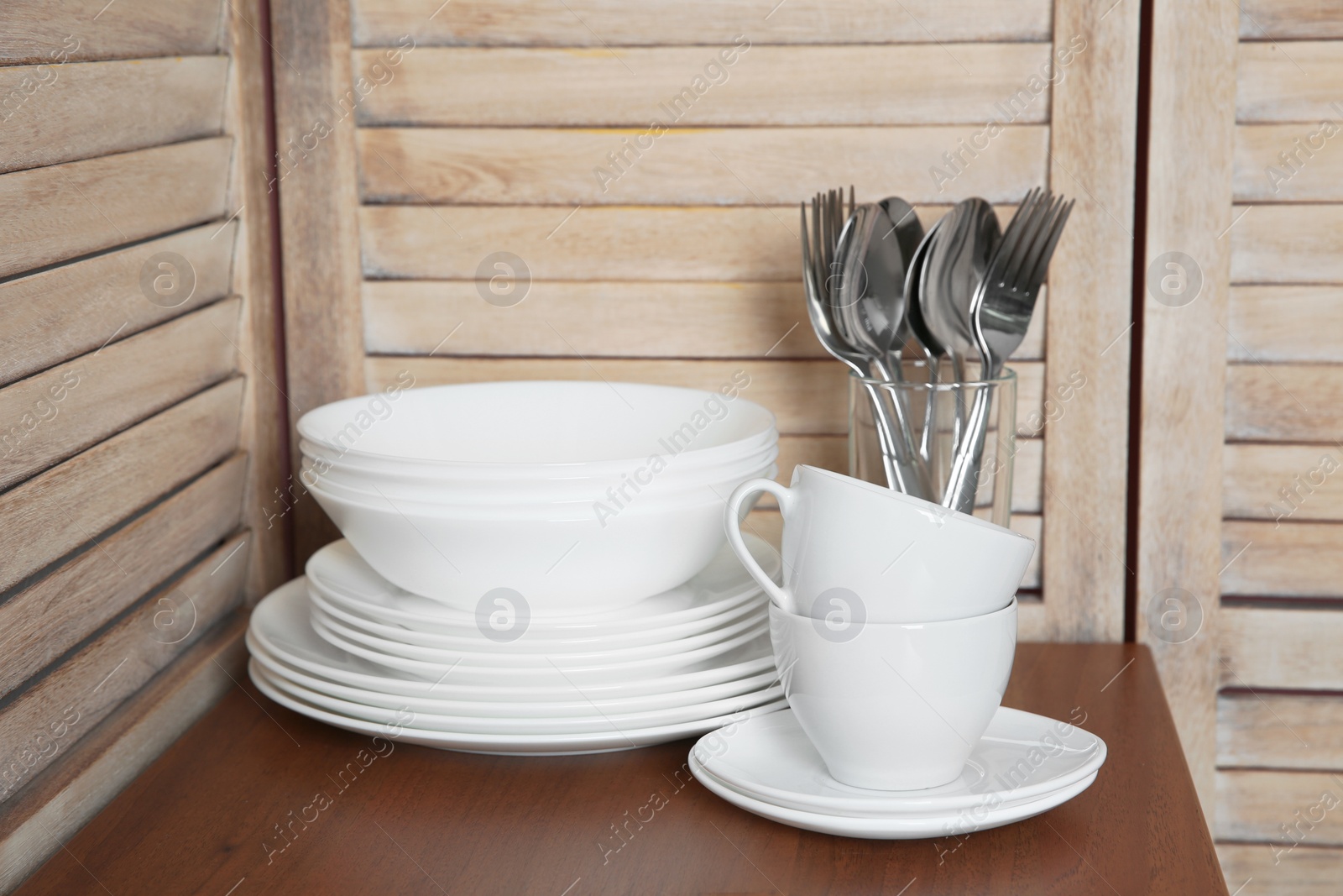 Photo of Set of clean dishes and cutlery on table in kitchen