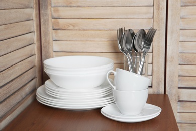 Set of clean dishes and cutlery on table in kitchen