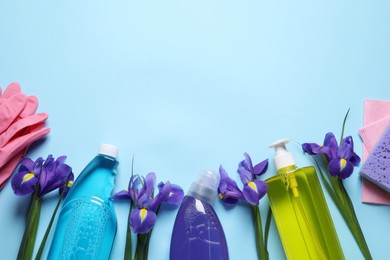 Photo of Spring cleaning. Detergents, flowers and tools on light blue background, flat lay. Space for text