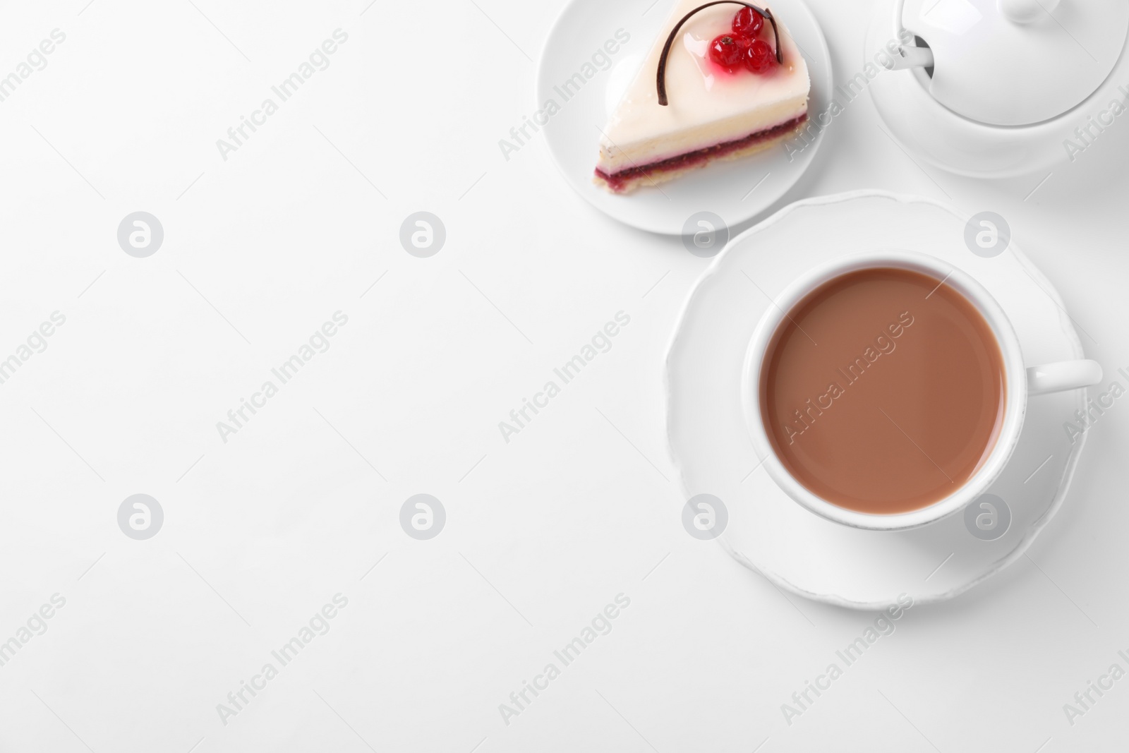 Photo of Delicious tea with milk in cup near dessert on white background, flat lay. Space for text