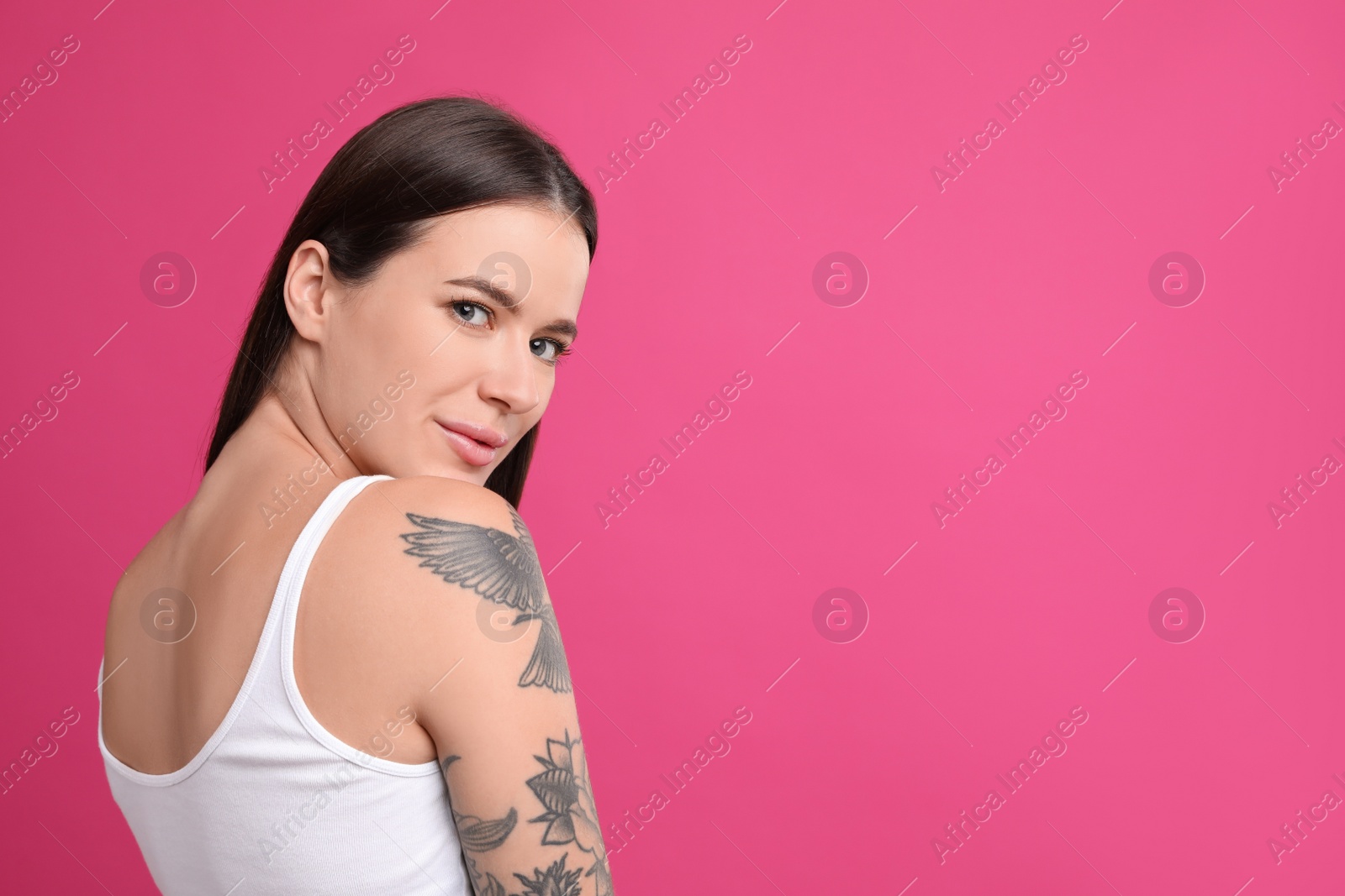 Photo of Beautiful woman with tattoos on arm against pink background. Space for text