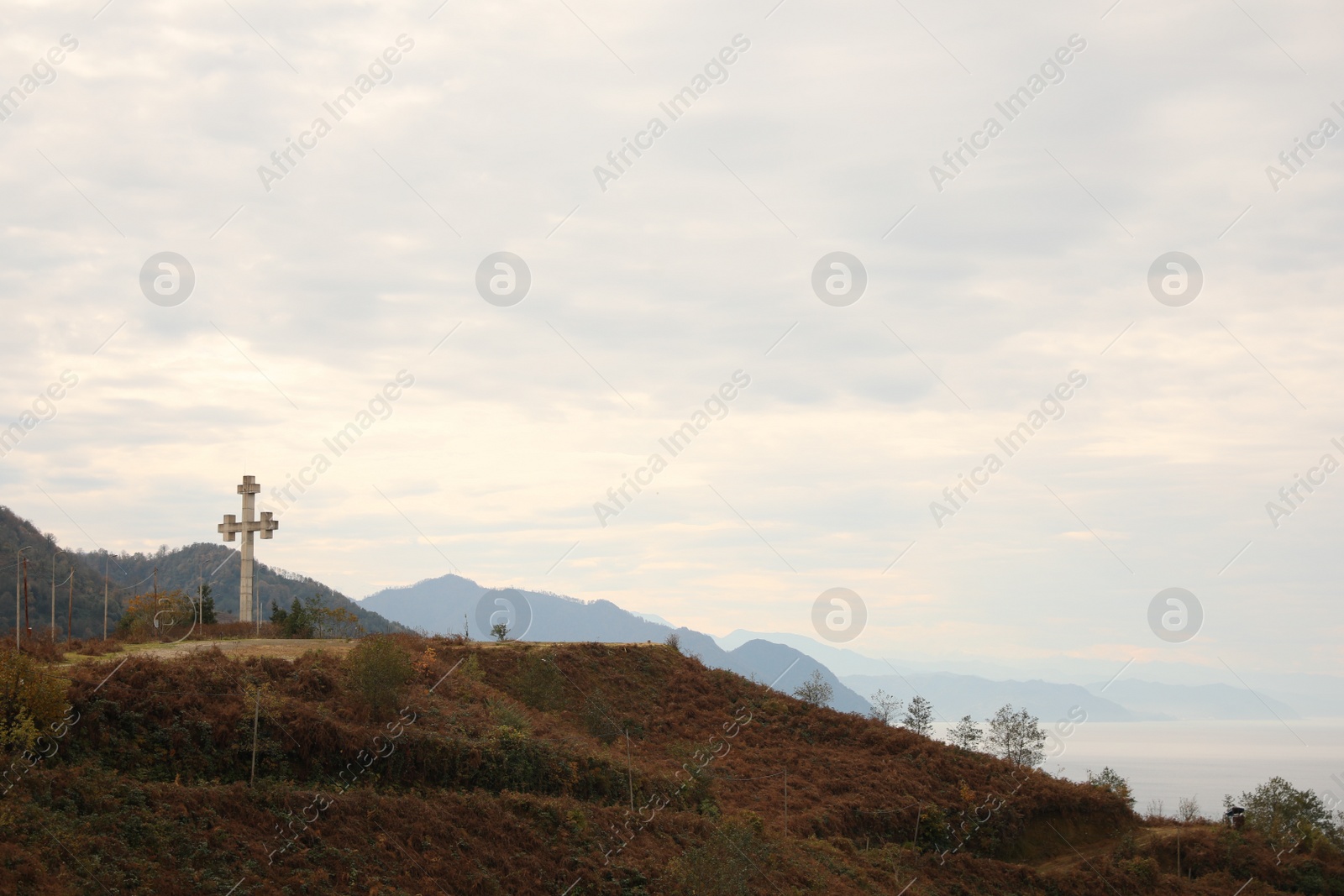 Photo of Picturesque view of beautiful sea, mountains and old cross under cloudy sky