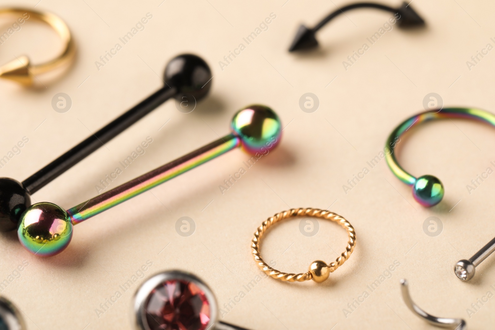 Photo of Stylish piercing jewelry on beige background, closeup